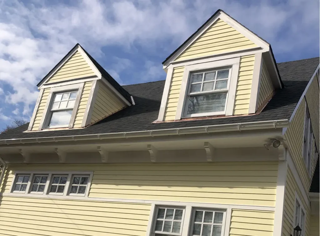 Gutter system on a two story house with yellow siding.
