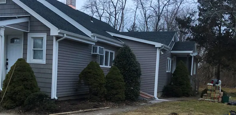 Gutter system on two homes with gray siding.
