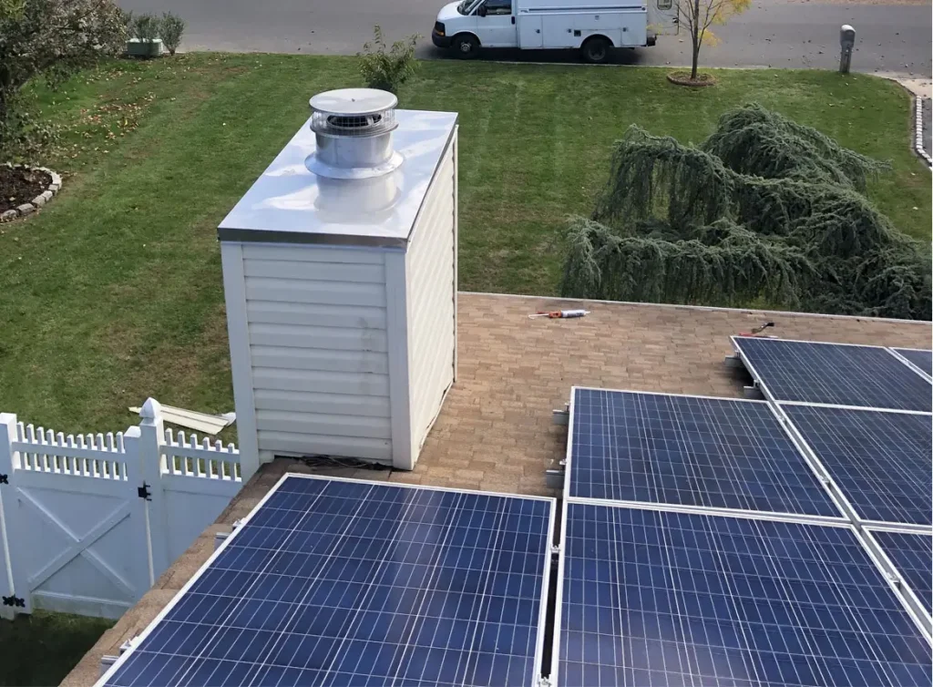 Metal and wood chimney and solar panels on top of a roof.
